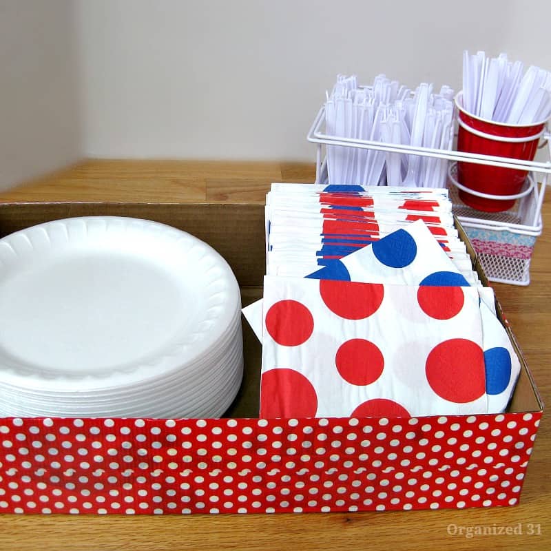 red and white polka dot decorated box holding paper plates and napkins.