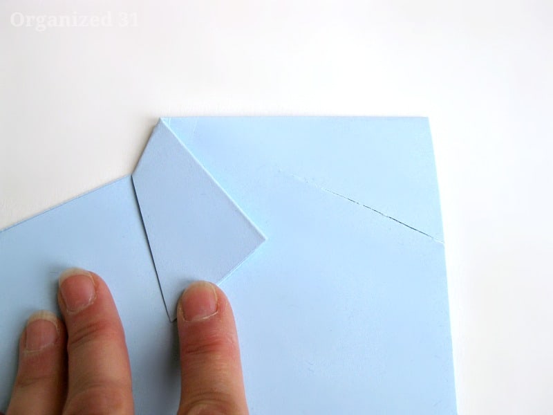 hand folding blue paper into shape of dress shirt.