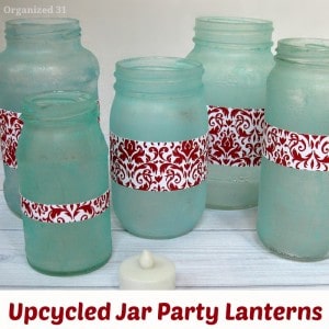 beach glass jars with red labels and tea light on table with title text reading Upcycled Jar Party Lanterns
