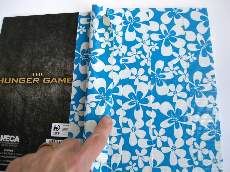 finger pointing to spine on blue and white floral tape covered journal