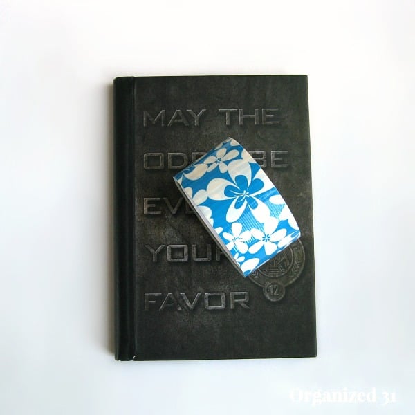 black journal with role of blue and white floral duct tape on white table