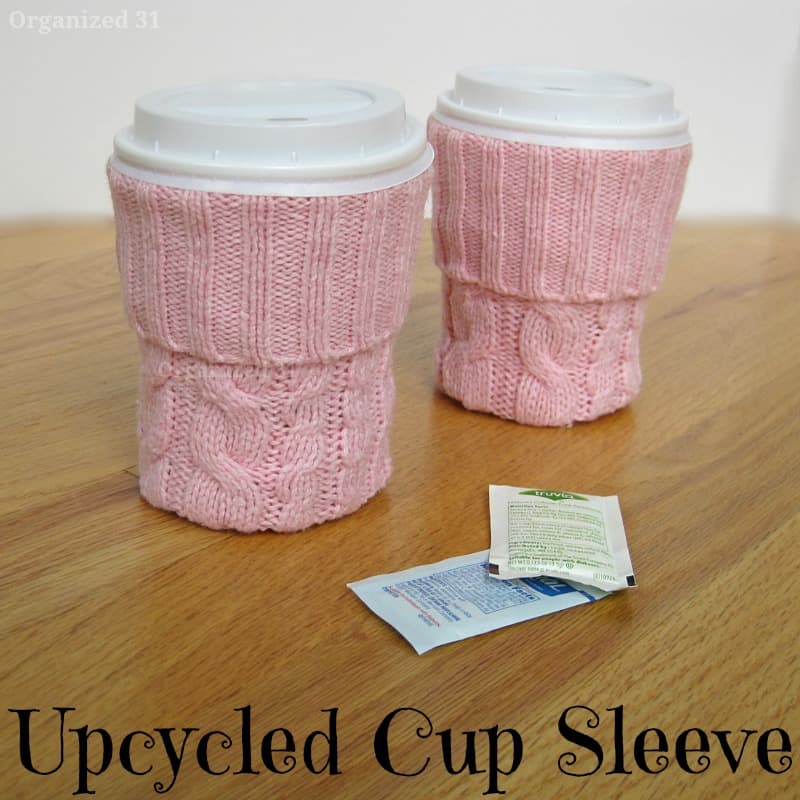 2 coffee cups with pink knit sleeves on wood table with 2 packets on sugar with title text reading Upcycled Cup Sleeve