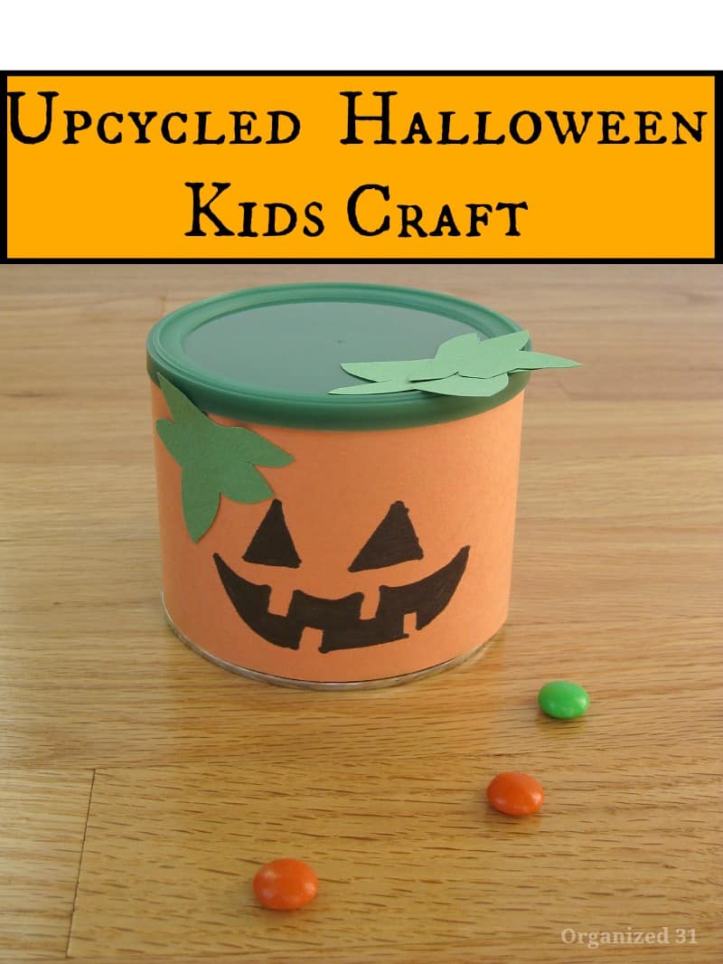paper craft jack o'lantern can with candy scattered on wood table
