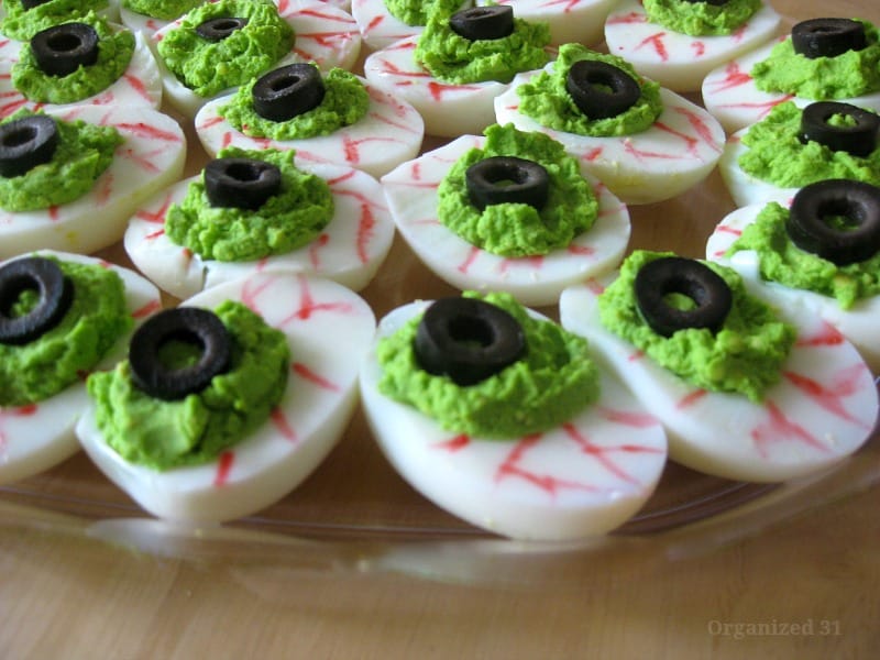 close up of deviled eggs decorated to look like spooky eyeballs