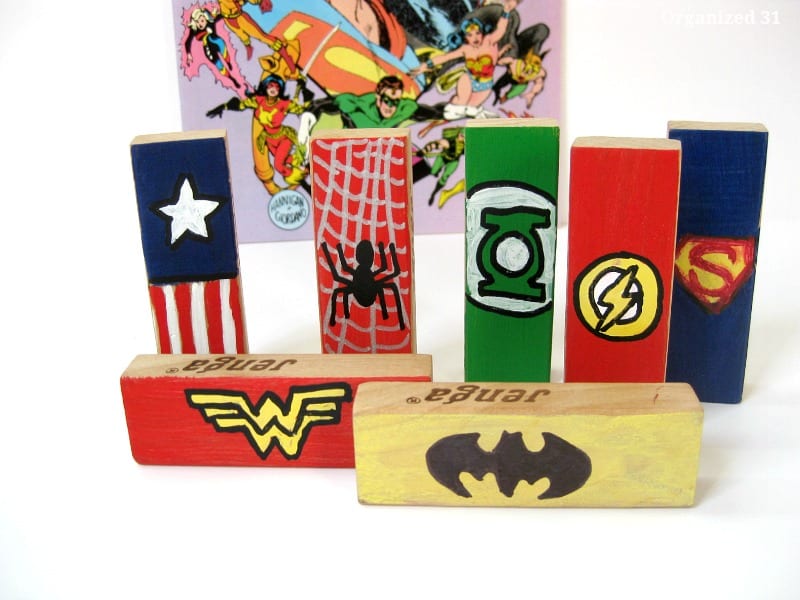 close up of wood game blocks painted with superhero logos next to comic book