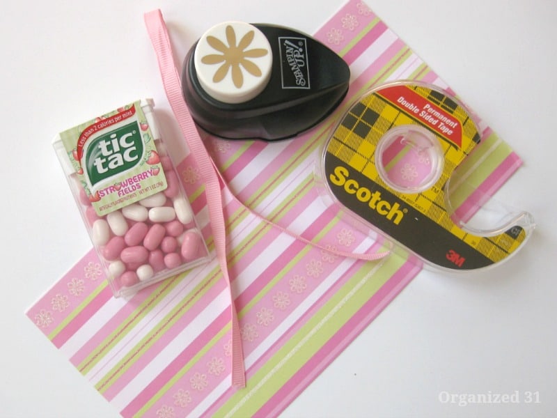 pink striped paper, box of pink tic tabs, pink ribbon, flower paper punch and roll of tape