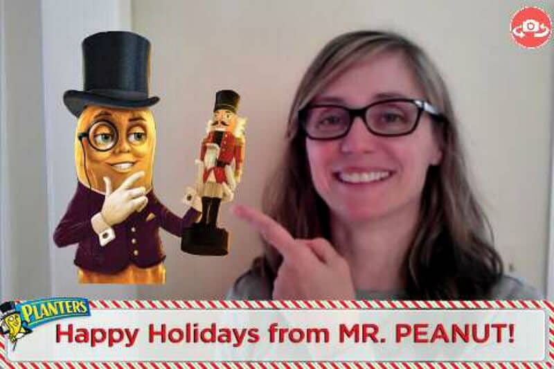 smiling woman pointing at Mr. Peanut holding a nutcracker