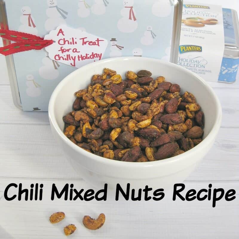 white bowl of spiced nuts in front of decorated tin with gift tag