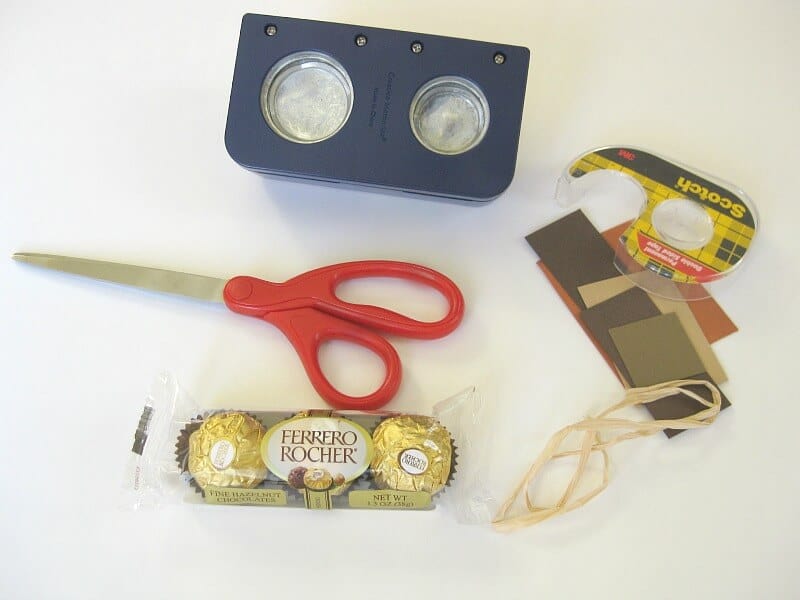 circle paper punch, double stick tape, scissors, brown paper, raffia and package of round gold foil candy