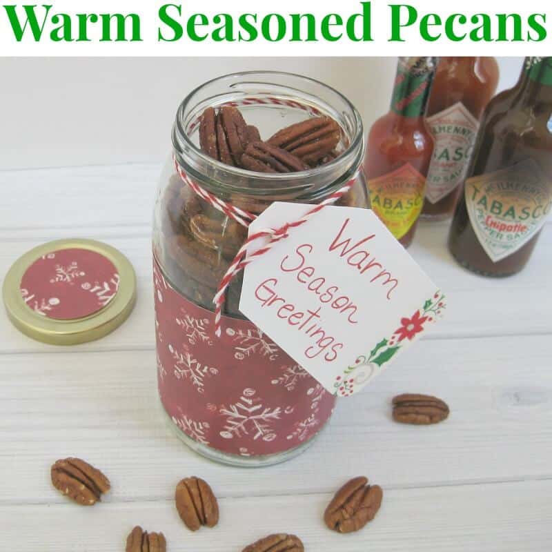 Pecans in decorated glass jar with bottles of hot sauce in background