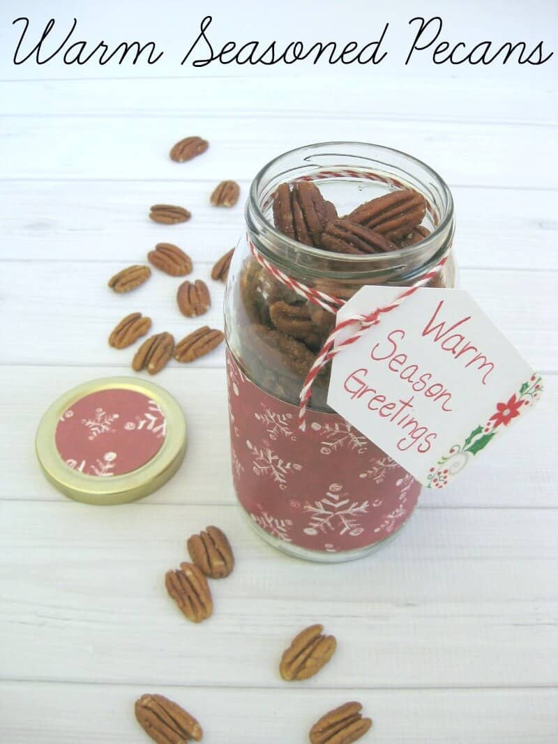 jar decorated with red winter themed paper and filled with spiced pecans with gift tag tied to bottle