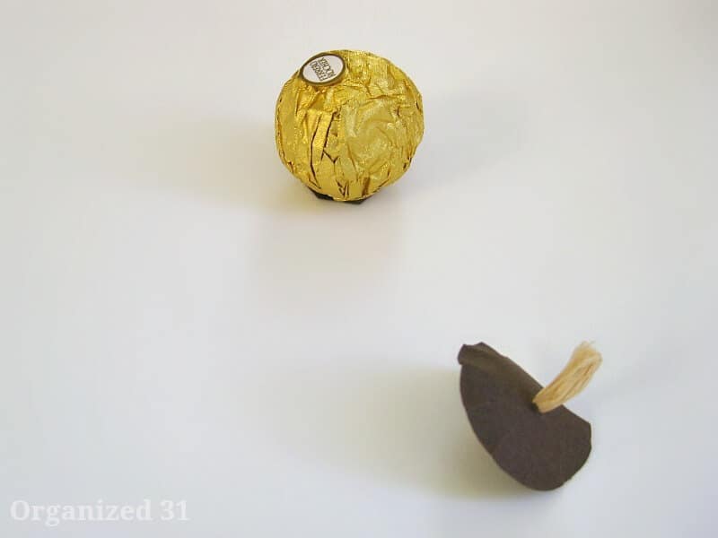 gold foil candy ball next to  paper acorn cap on white table