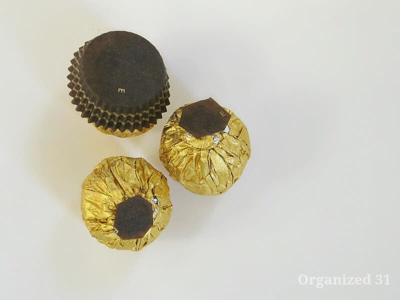 3 gold foil candy balls with brown paper cup removed from two of them