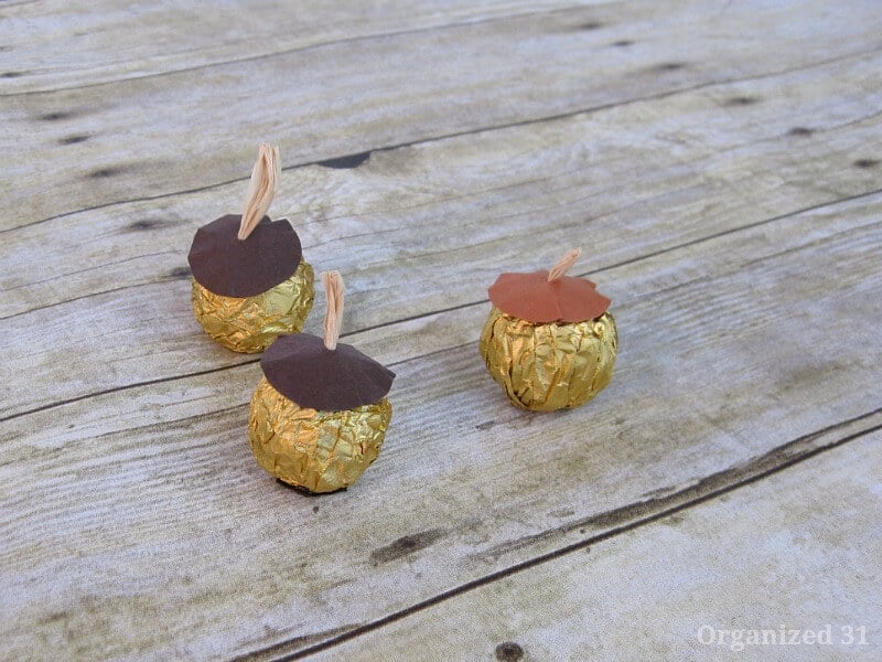 close up of three crafted candy acorns on rustic wood table