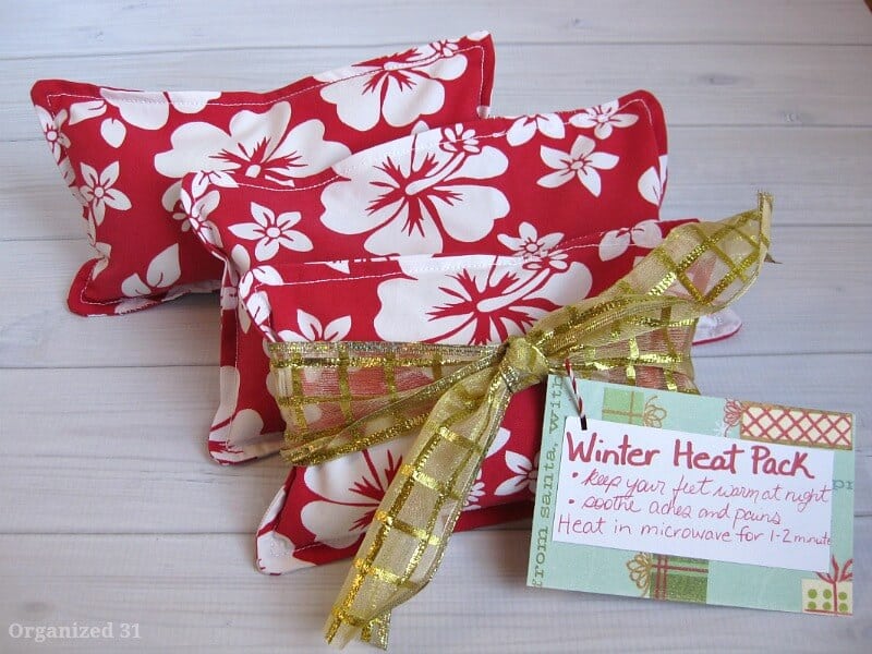 close up of 3 red and white floral squares with tag that says "winter heat pack" on white wood table