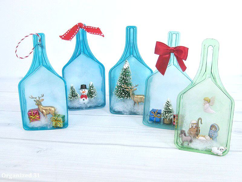 5 plastic laundry scoops decorated with different Christmas scenes made from tiny decorations