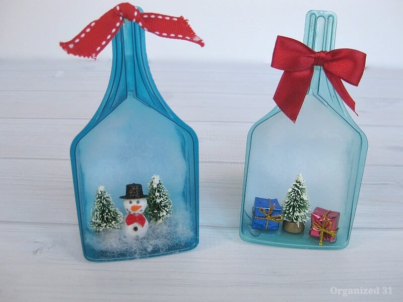 2 blue laundry scoops decorated with mini Christmas trees, gifts and a snowman