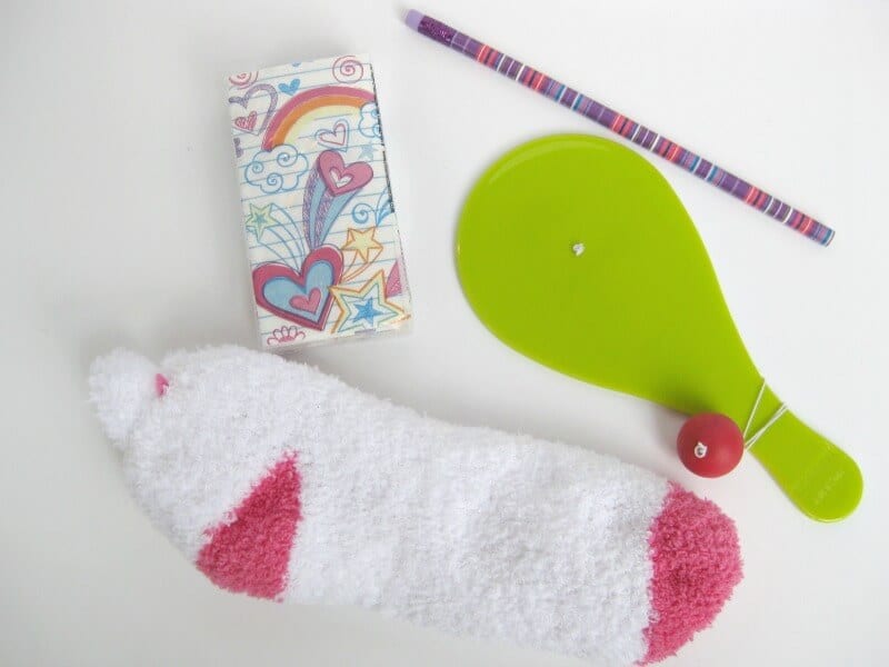 white and pink fuzzy socks, rainbow decorated pack of tissues, brightly striped pencil, green paddle ball toy