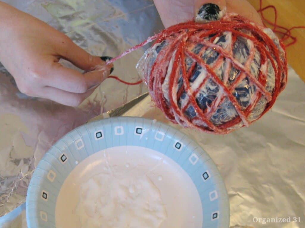 bowl of decoupage glue with twine wrapped around balloon