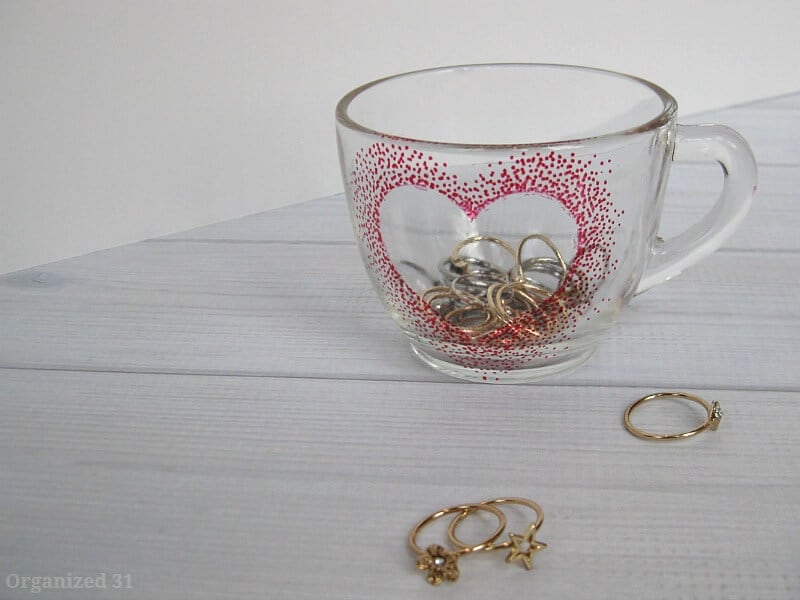 clear cup with red dot heart holding rings