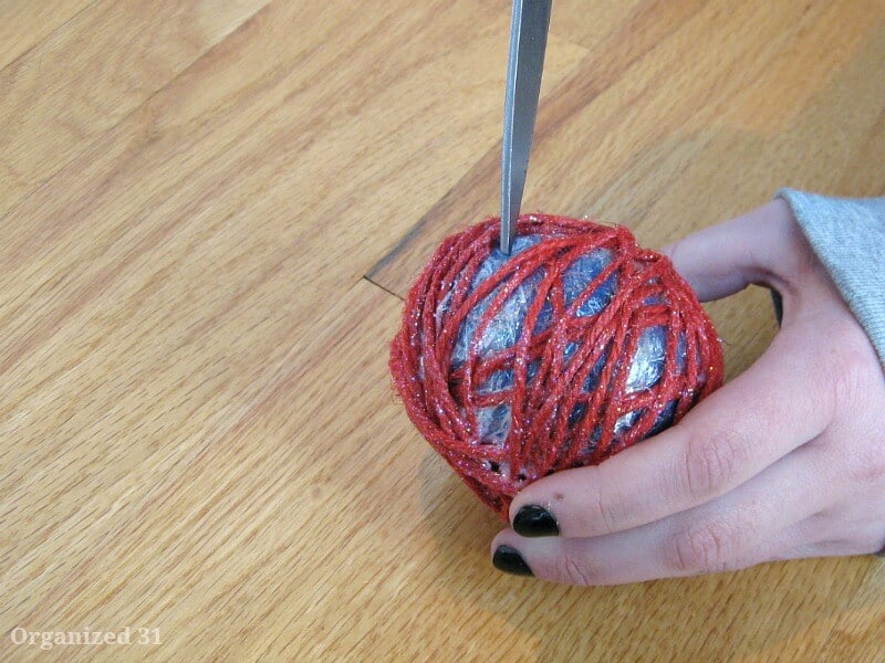 Scissors about to pierce balloon of diy twine ball