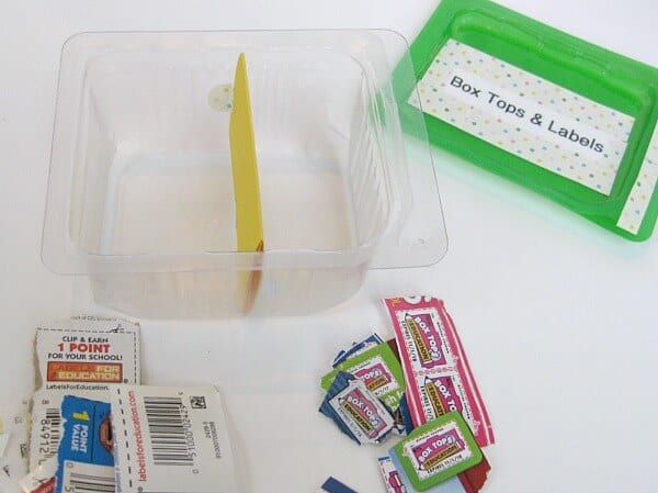 plastic container with cardboard divider added . two neat piles of cut out box top coupons