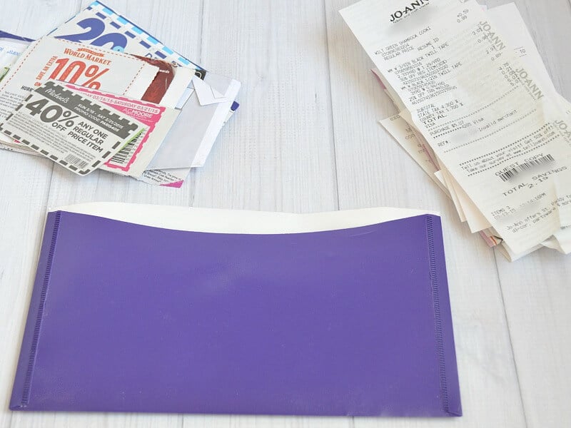 purple envelope with 2 stacks of receipts on white wood table