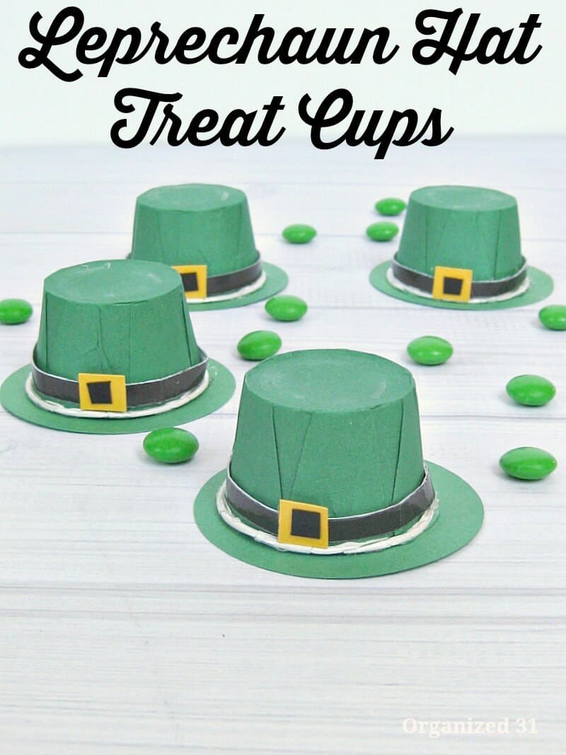 crafted green paper hats with black strap and buckle and green candies scattered on white wood table