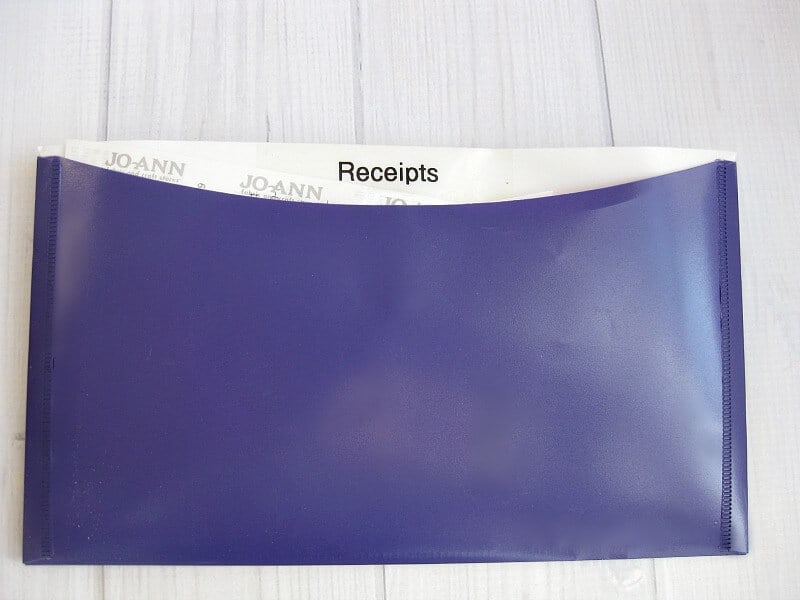 purple envelope labeled "receipts" on white wood table