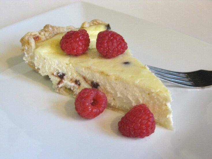 slice of Cannoli Pie with raspberries on white plate with fork.