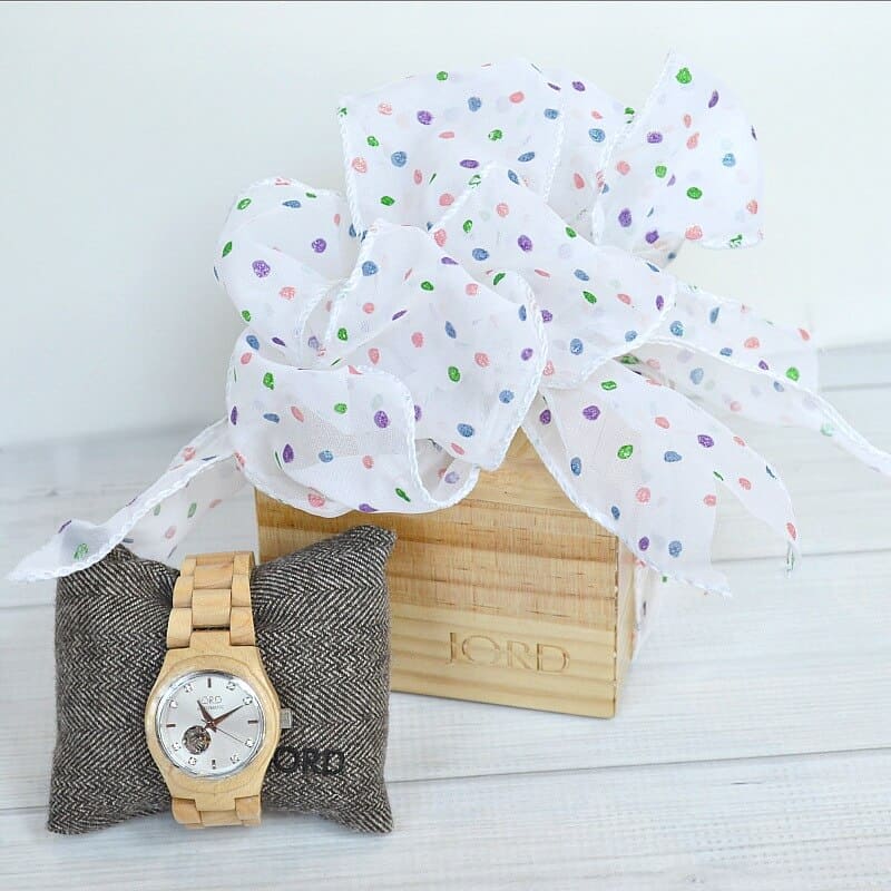 wood watch on grey pillow with wood box tied with white and pastel polka dot bow