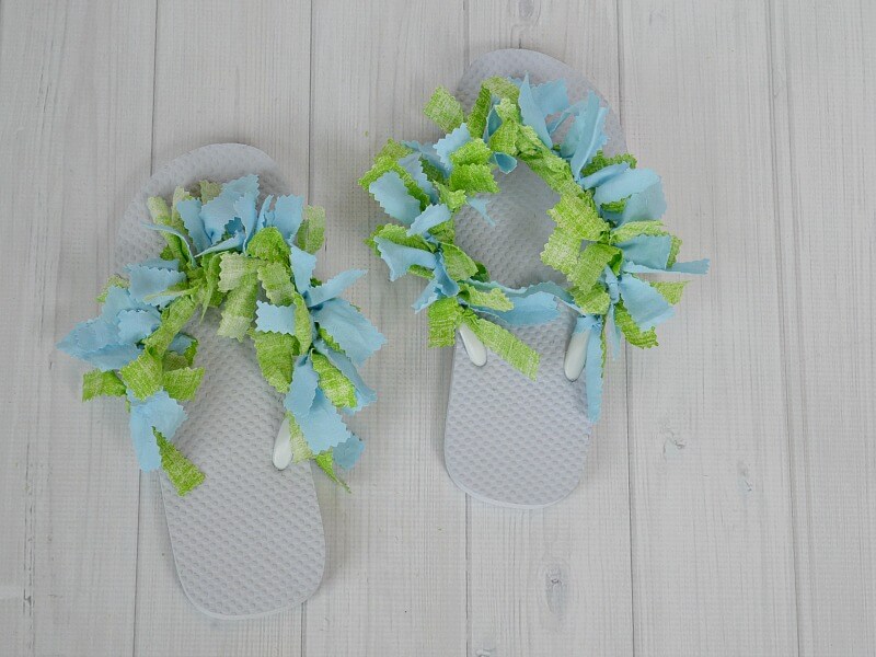 overhead view of white flip flops with green and blue embellishment