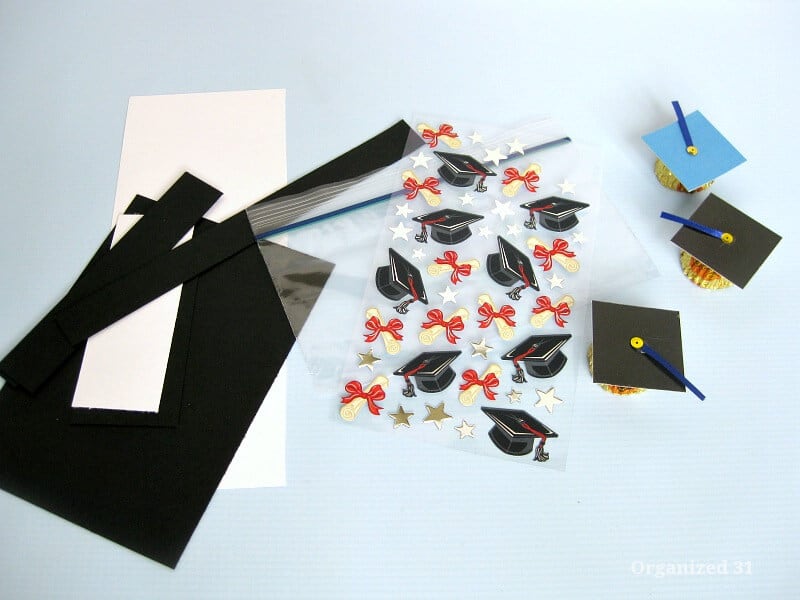 black and white paper scraps, sheets of graduation cap labels and 3 pieces of decorated graduation cap candies
