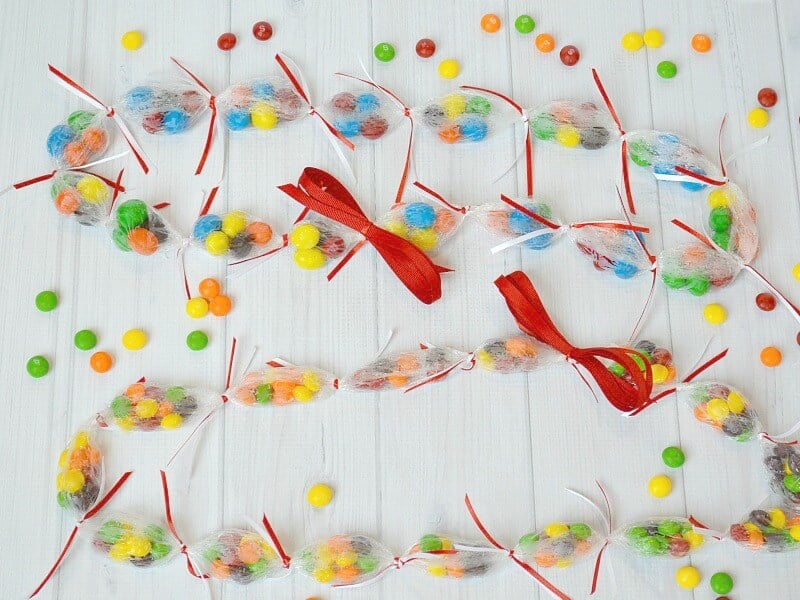 overhead view of 2 candy leis with colorful candies scattered on white wood table
