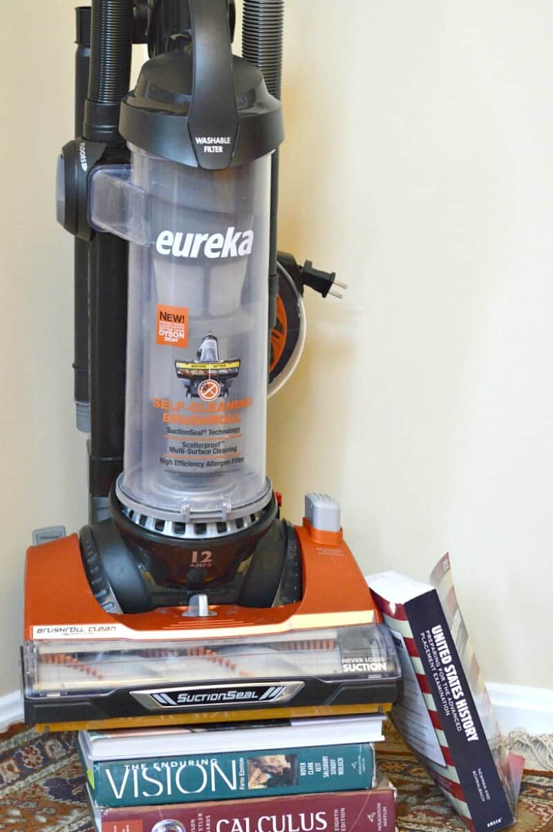 orange and black vacuum standing on top of pile of college text books