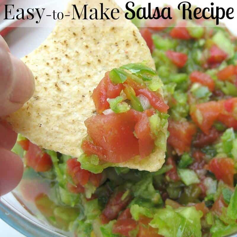 hand holding tortilla chip and scooping up red and green salsa.