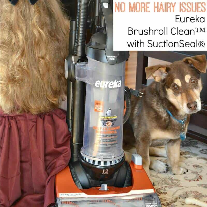 orange and black vacuum cleaner with girls with long hair on one side and brown and tan dog looking at camera on other side