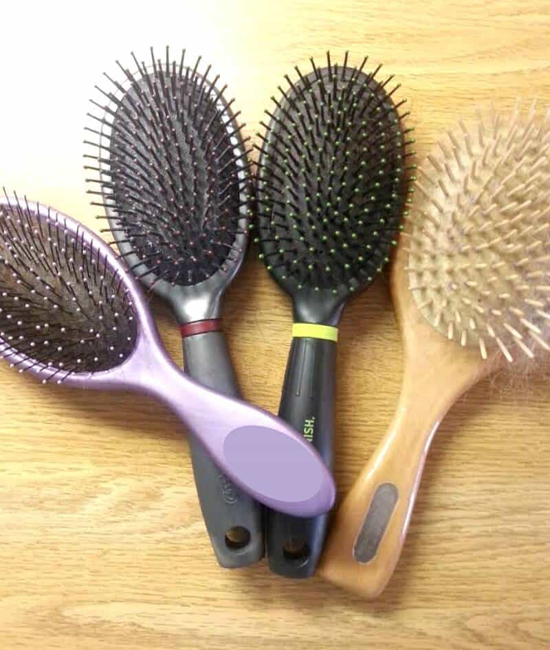 4 Hair brushes with hair tangled in bristles on wood table