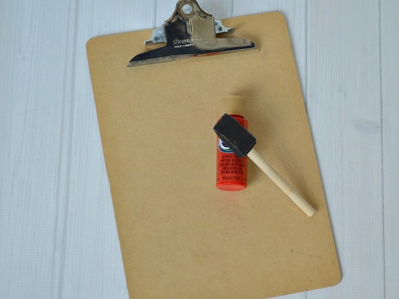 wood clipboard with bottle of craft paint and sponge brush on top