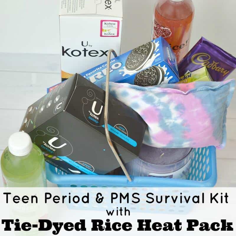 blue basket filled with cookies, candy, tampons and a purple and blue rice heat pack with bottles of juice near by