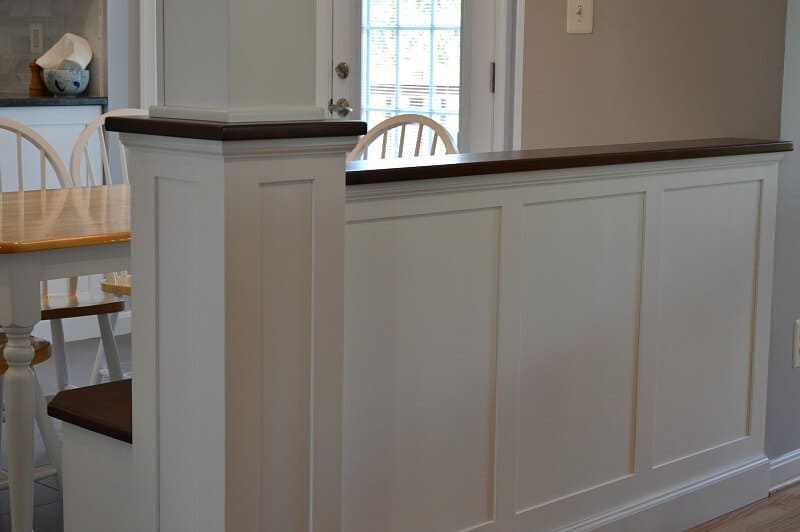 White half wall with molding and wood top.