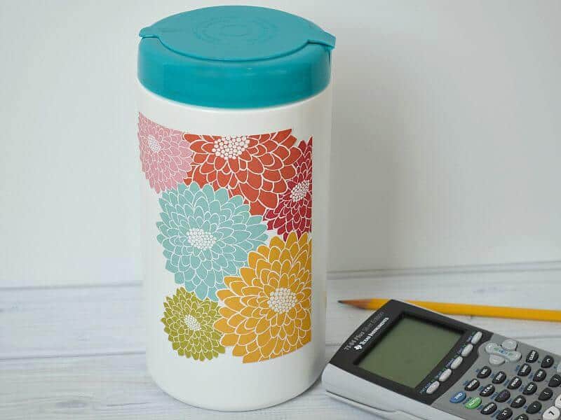 disinfecting wipes container decorated with colorful flowers  on white wood table next to calculator  and pencil