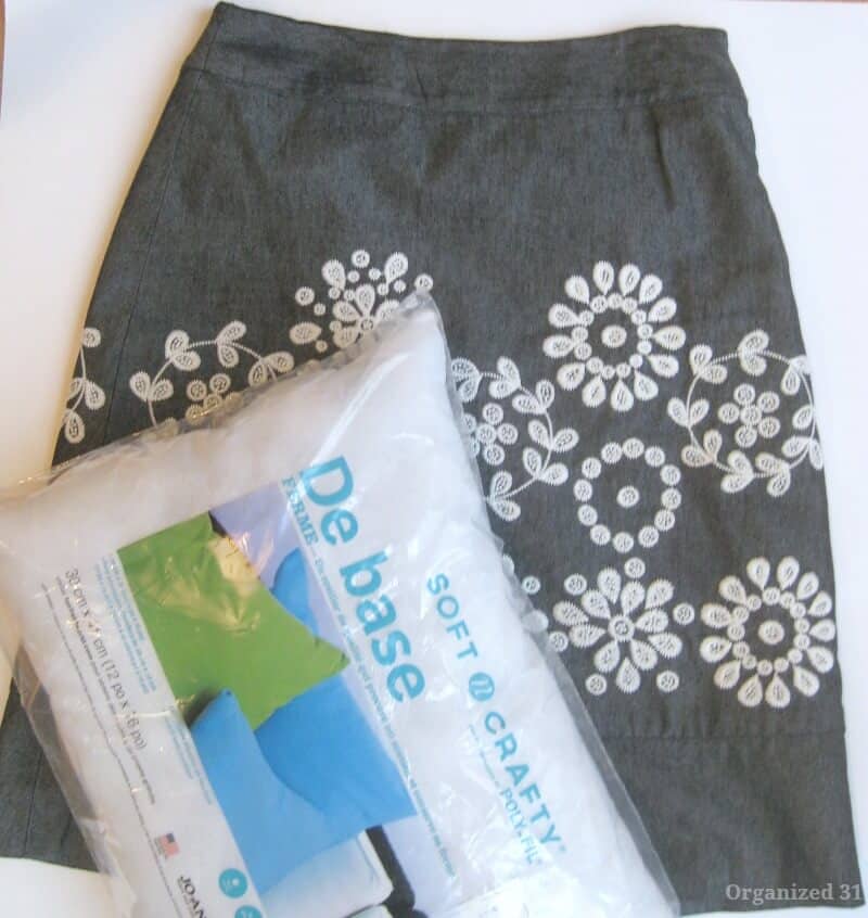 overhead view of grey skirt with white flowers and pillow form in plastic bag