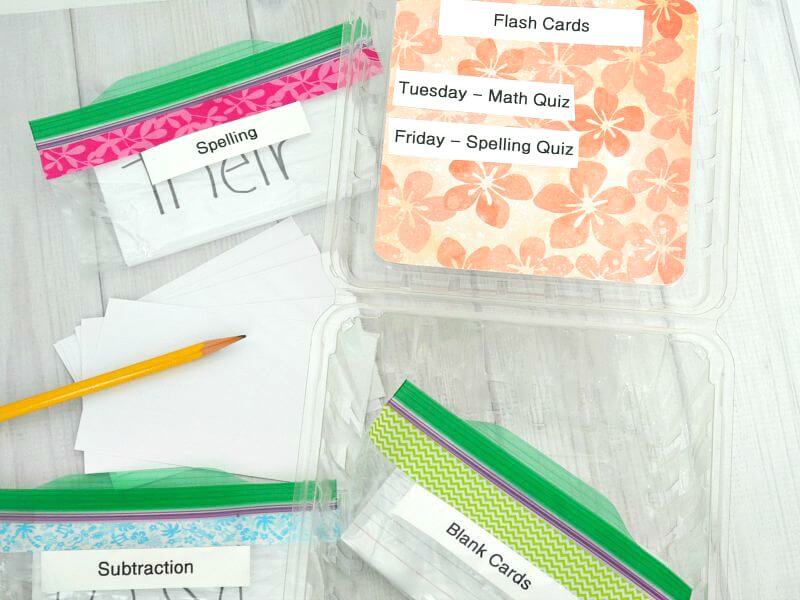 stack of index cards with pencil  next to plastic food zippered bags with labels saying spelling, subtraction and blank cards next to box lid that says "Flash cards, Tuesday - math quiz and Friday - spelling quiz"