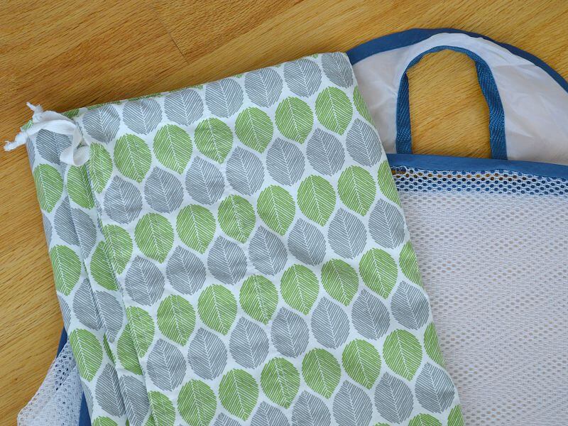 folded mesh and blue laundry basket with folded green and grey leaf cloth bag