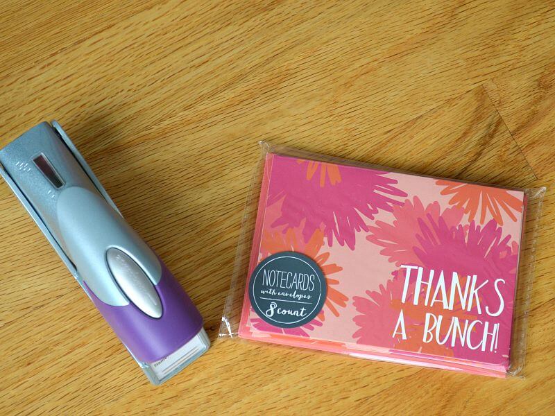 overhead view of purple stapler and pink floral thank you cards on wood table