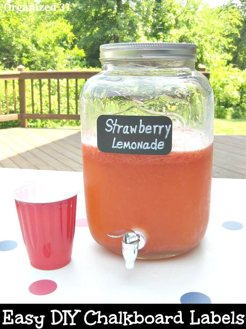 large jar of red lemonade with red cup on table on a deck outside