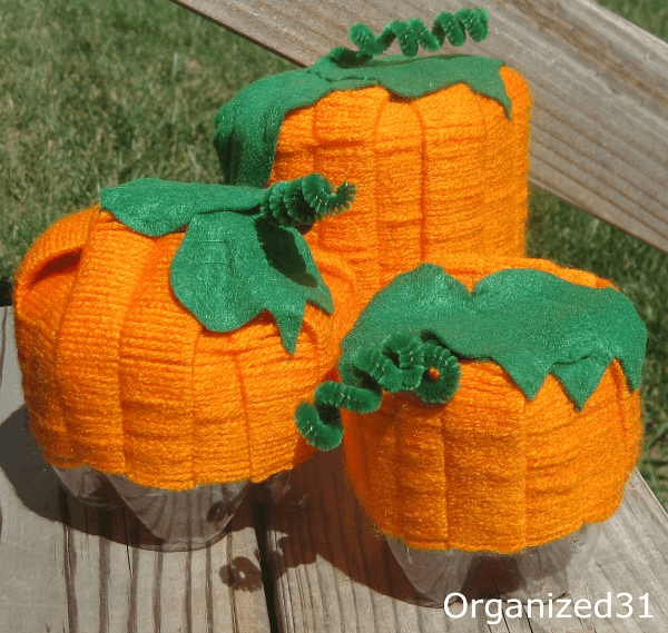 3 DIY yarn and felt pumpkins on wood table.