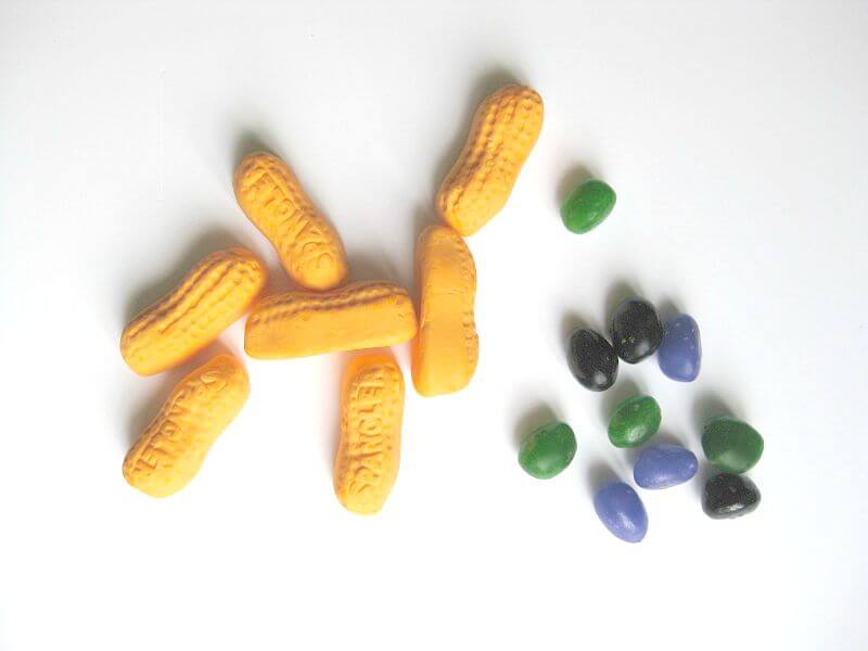 orange circus peanuts candy next to black, purple and green jelly beans