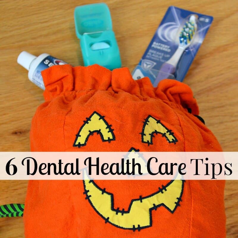 orange jack o'lantern bag on wood table with toothpaste, toothbrush and dental floss at top of bag